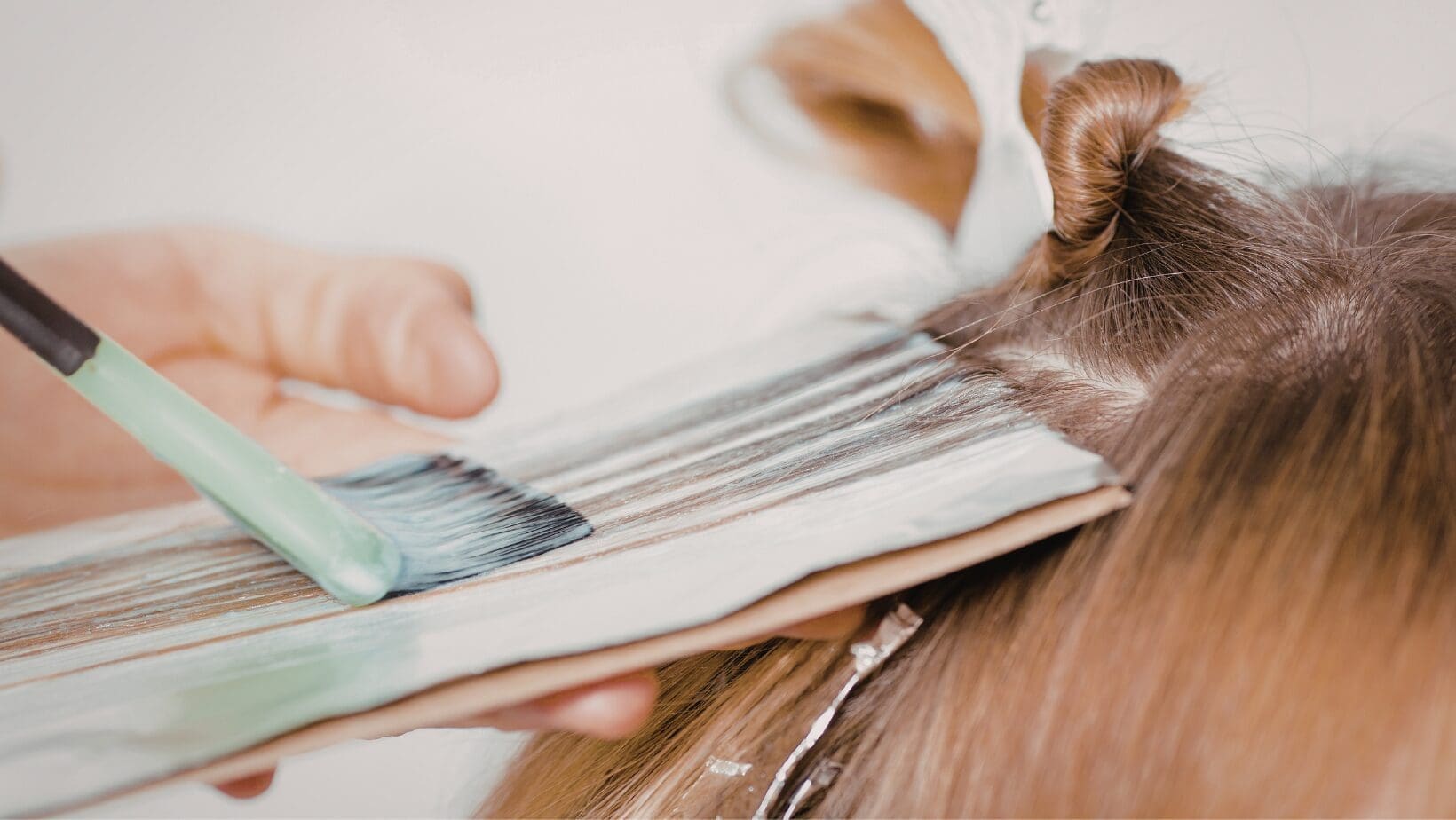 Hair stylist applying professional hair color to a guest at The Red Stiletto salon in Fort Wayne.