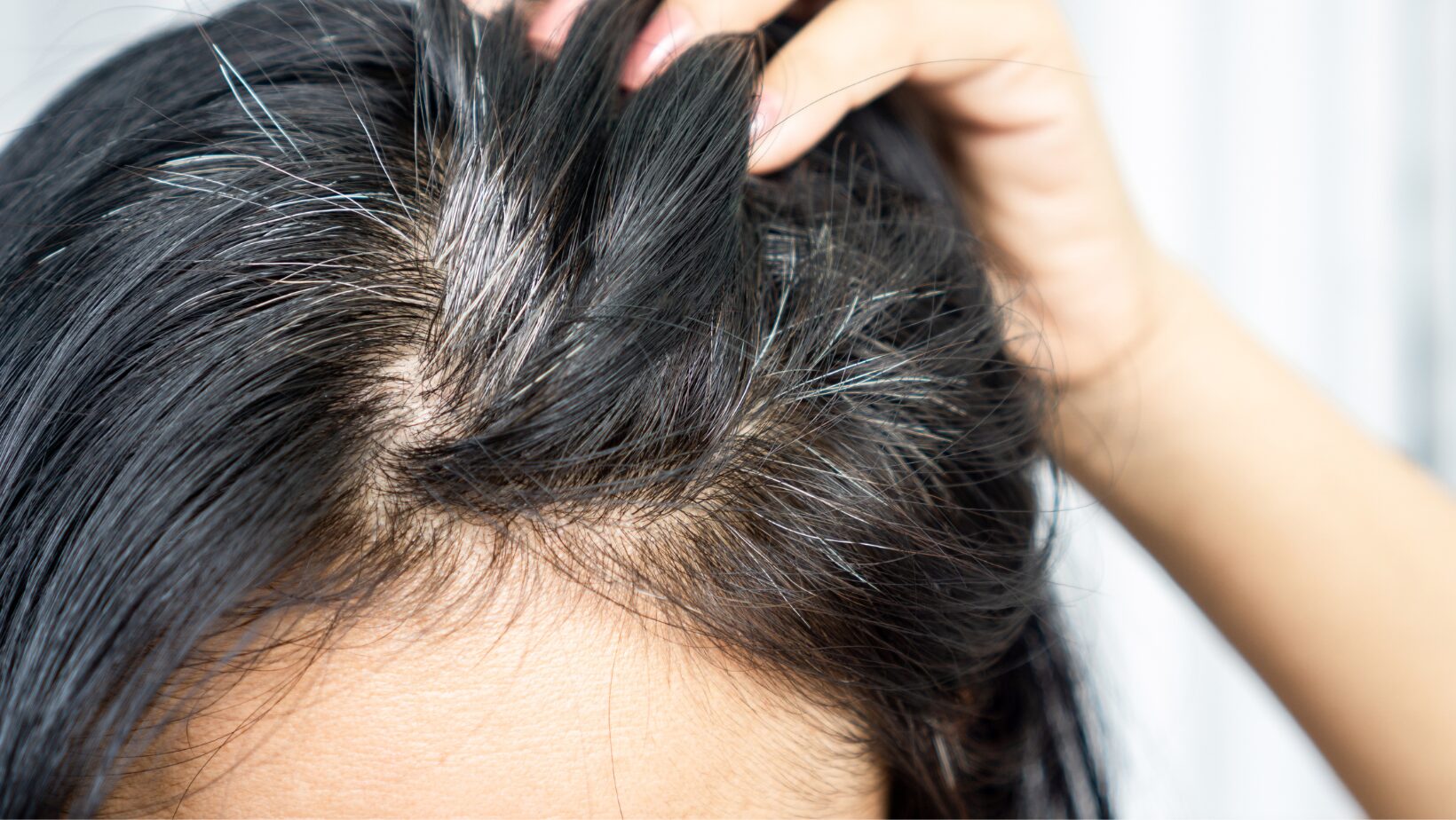 Professional hairstylist applying gray coverage color to hair during a salon appointment.
